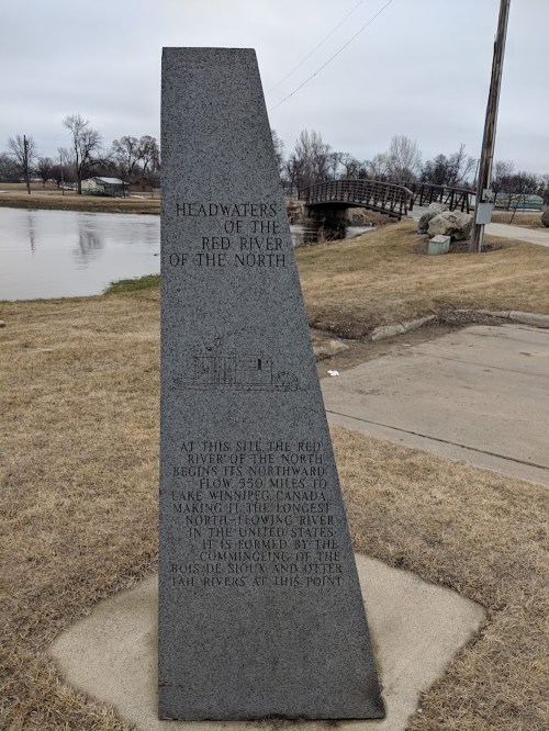 Monument marking the headwaters of the Red River of the North, with text detailing its significance and location.