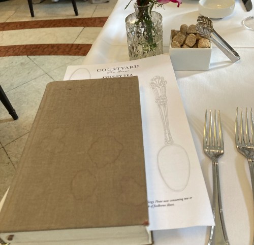A table setting with a menu, a vase of flowers, and a small bowl of sugar cubes in a restaurant.
