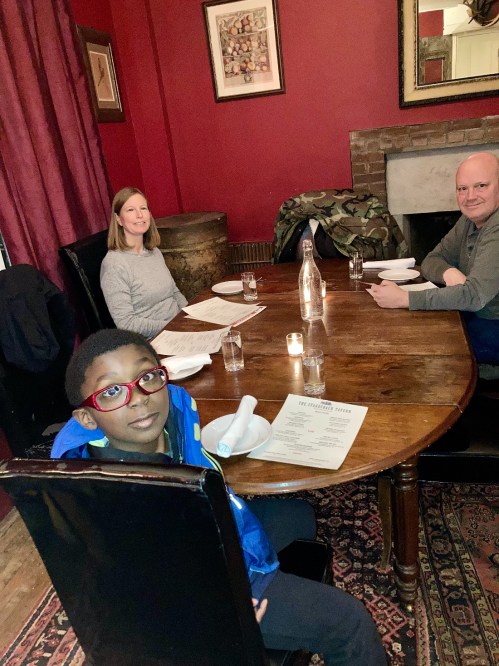 A family sits at a wooden table in a cozy restaurant, with menus and candles on the table.