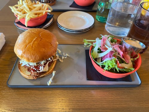 A plate with a burger, salad, and fries on a wooden table.