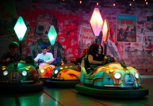 A vibrant scene of people enjoying bumper cars in a colorful, graffiti-decorated amusement venue.