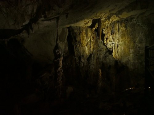 Dimly lit cave interior with stalactites and rocky formations, creating an eerie and mysterious atmosphere.