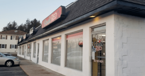 Exterior of a sushi restaurant with large windows and a sign reading "Sushi Red," located in a strip mall.