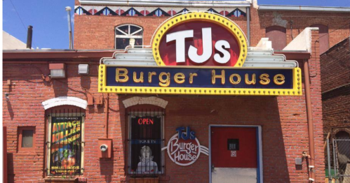 A brick building with a bright sign reading "TJ's Burger House" and an open sign in the window.