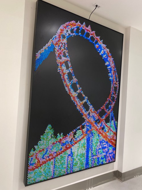 A colorful digital display of a roller coaster loop against a dark background.