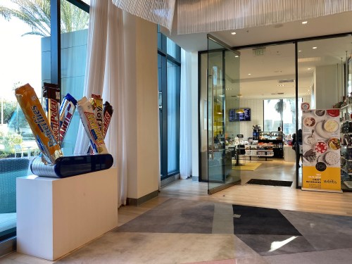 A modern store entrance featuring a display of large candy bars and a bright, inviting interior.