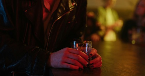 A patron in a leather jacket holds a drink in the low-lit, atmospheric interior of a Missouri speakeasy.