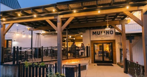 A cozy outdoor dining area of a restaurant with string lights and patrons enjoying their meal.