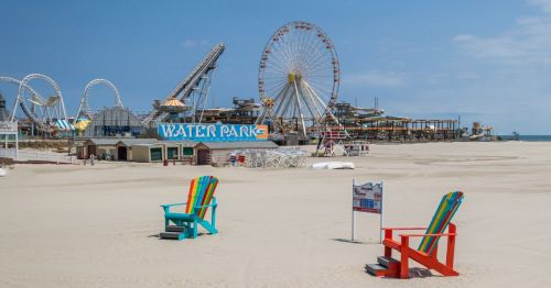 Wildwood Park New Jersey beach with adirondack chairs in the foreground and Ferris wheel and amuesment park rides in the background