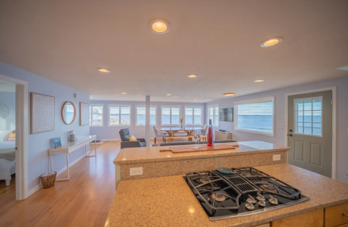 Bright, open-concept living space with a kitchen island, large windows, and a view of the water. Cozy and inviting atmosphere.