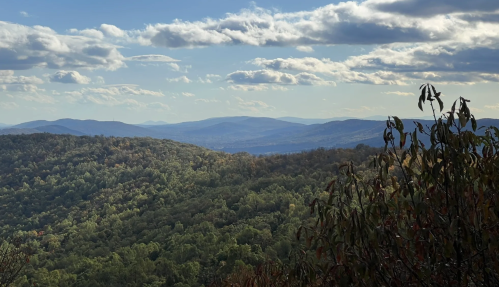 A panoramic view of rolling green hills under a partly cloudy sky.
