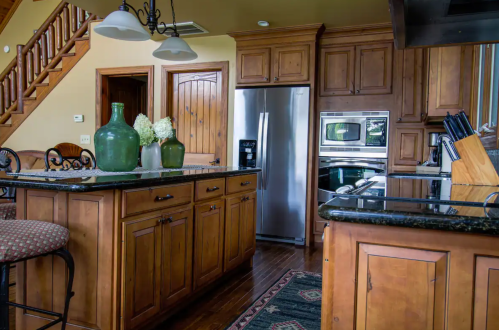 A warm, wooden kitchen featuring an island, stainless steel appliances, and decorative vases on the counter.