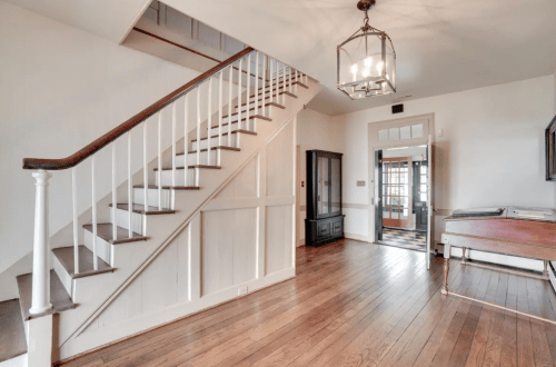 Bright entryway featuring a staircase, hardwood floors, and a decorative light fixture.