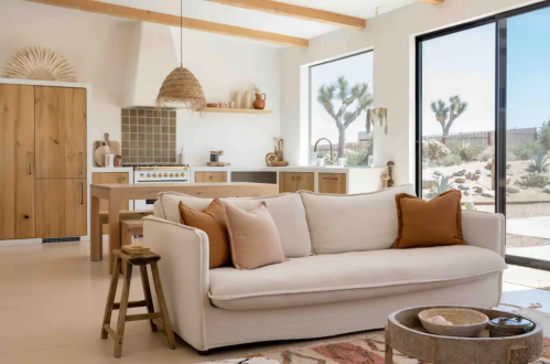 Bright, modern living space featuring a white sofa, wooden accents, and large windows with desert views.