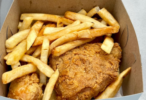 A takeout box filled with golden fried chicken and crispy French fries.