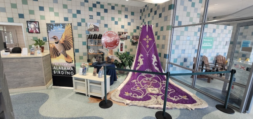 Interior of a welcoming space featuring a large purple rug, birding displays, and seating areas.