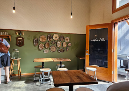A cozy café interior with wooden tables, stools, and decorative plates on the wall, featuring a door labeled "Rafiki & Co."