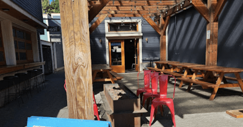 Outdoor dining area with wooden tables, red chairs, and a sign for "Pastificio d'Oro" featuring pasta and wine offerings.