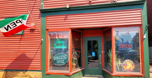 A colorful storefront with large windows displaying "OPEN" and "Papa Frank's" signs, featuring a flag outside.