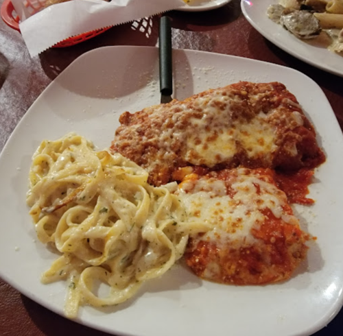 A plate featuring cheesy lasagna, marinara sauce, and creamy fettuccine alfredo.