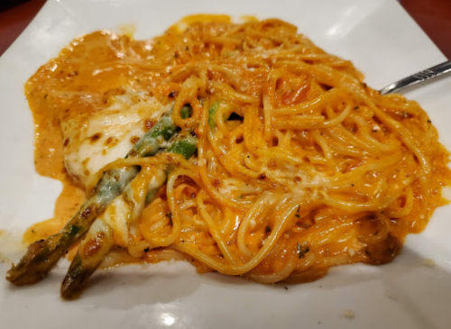 Creamy pasta with asparagus, topped with cheese, served on a white plate.