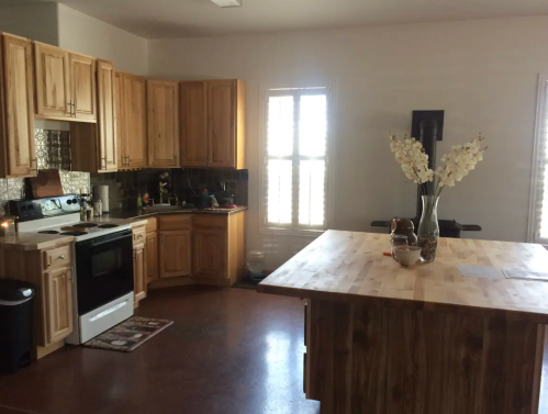 Bright kitchen with wooden cabinets, a central island, and a vase of flowers on the counter.