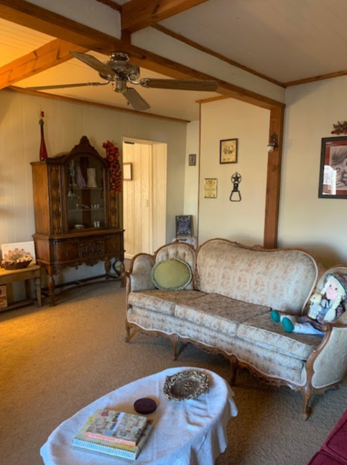 Cozy living room with vintage furniture, a decorative cabinet, and a plush sofa adorned with a doll.