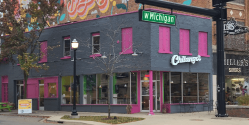 Colorful restaurant exterior with pink and green accents, located on a street corner with a sign for W Michigan.