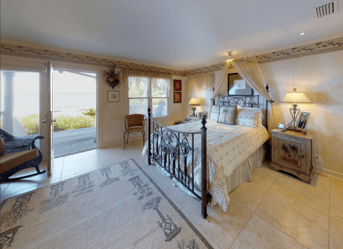 Cozy bedroom with a wrought iron bed, soft lighting, and a view of the outdoors through glass doors.