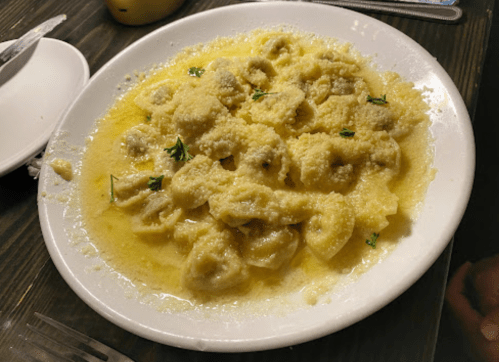 A plate of pasta with a creamy sauce, topped with grated cheese and garnished with herbs.
