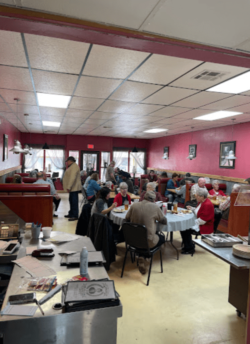 A busy restaurant interior with patrons seated at tables, chatting and enjoying meals in a cozy atmosphere.