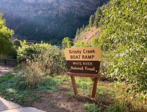 Sign for Grizzly Creek Boat Ramp in White River National Forest, surrounded by greenery and mountains in the background.