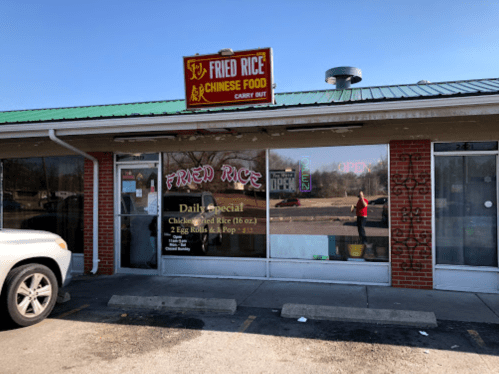 Exterior of a Chinese food carry-out restaurant named "Fried Rice," featuring a sign and large windows with an open sign.