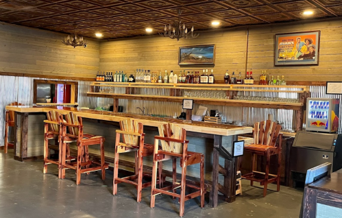 A rustic bar with wooden stools, shelves of liquor, and a warm, inviting atmosphere.