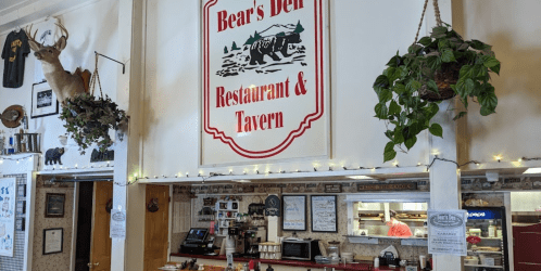 Interior of Bear's Den Restaurant & Tavern, featuring rustic decor, a deer mount, and a welcoming atmosphere.