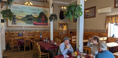 Cozy restaurant interior with wooden decor, a mural of a fisherman, and patrons enjoying their meals at tables.
