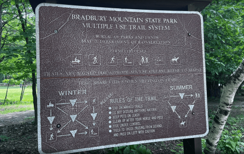 Sign at Bradbury Mountain State Park outlining trail rules and seasonal guidelines for visitors and pets.