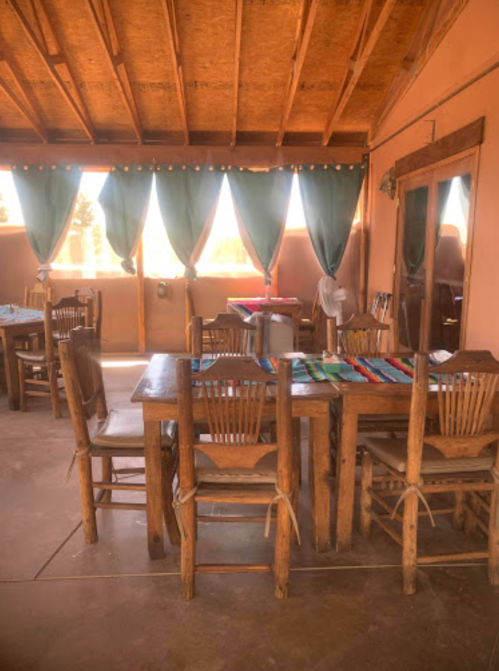 Cozy dining area with wooden tables and chairs, adorned with colorful table runners and curtains.