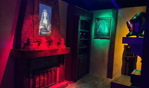 A dimly lit room featuring a fireplace, colorful lights, and framed artwork on the walls.
