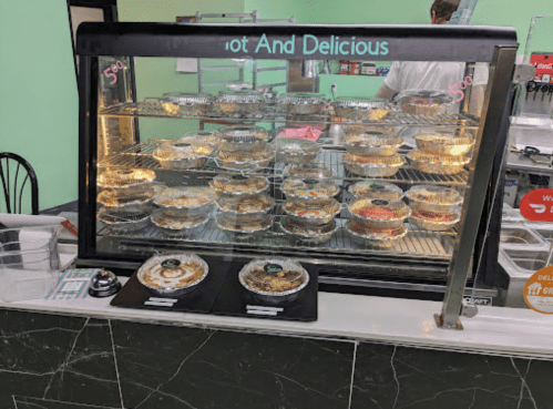 Display case filled with various food containers, labeled "Hot and Delicious," in a casual dining setting.