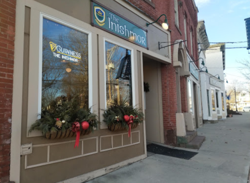 Exterior of The Highmor pub, featuring festive decorations and large windows, on a brick building in a quaint street.