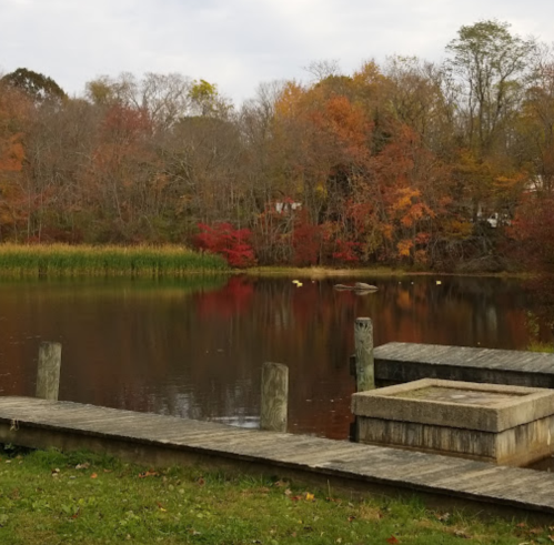 A serene lake surrounded by autumn foliage, with wooden docks and reflections on the water.
