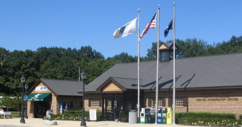 A visitor information center with flags flying outside, surrounded by trees and a clear blue sky.