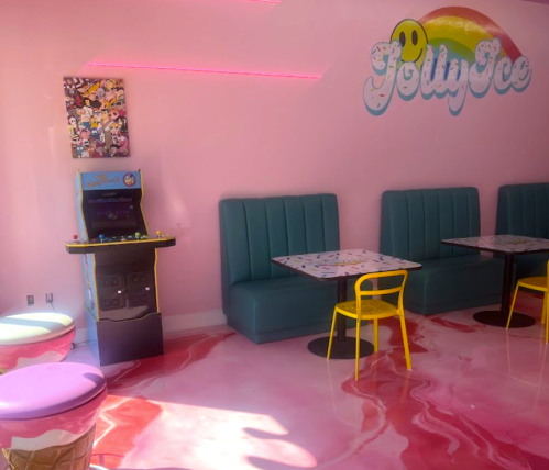 Colorful ice cream shop interior with pink walls, teal seating, and a retro arcade game. Bright and playful atmosphere.