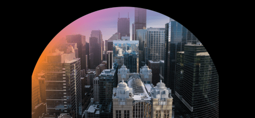 Aerial view of a city skyline with modern skyscrapers and a colorful sunset in the background.