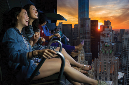 Two women enjoy a thrilling ride with a city skyline and sunset in the background, capturing a moment of joy and excitement.