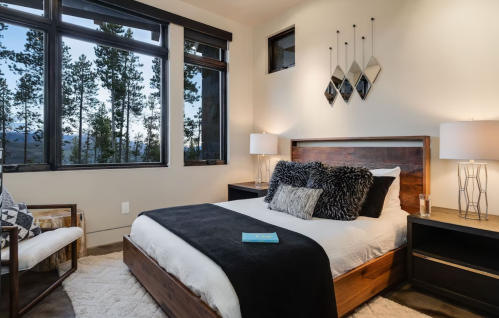 Cozy bedroom with a large window, mountain views, a plush bed, and stylish decor in neutral tones.
