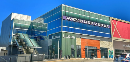Exterior view of a modern shopping center featuring "Wonderverse" signage and stores like L.L. Bean. Clear blue sky.