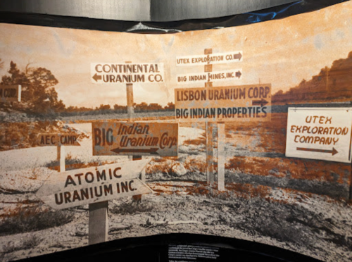 Historical photo featuring various signs for uranium companies, including Continental Uranium Co. and Atomic Uranium Inc.