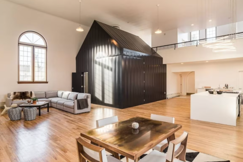 Modern open-concept living space featuring a black metal structure, cozy seating area, and a dining table.